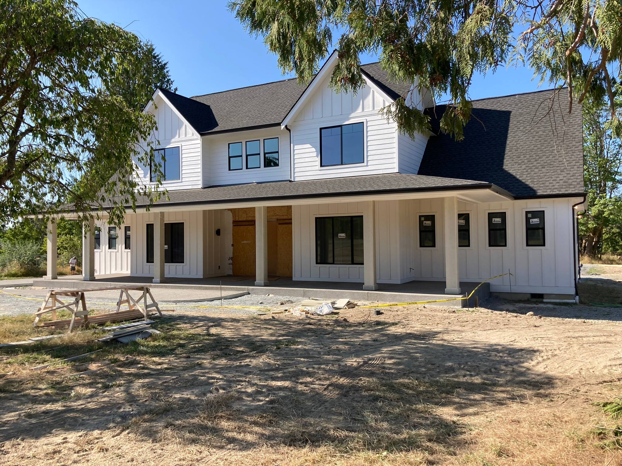 White modern farmhouse with vertical board and batten siding and a long covered porch