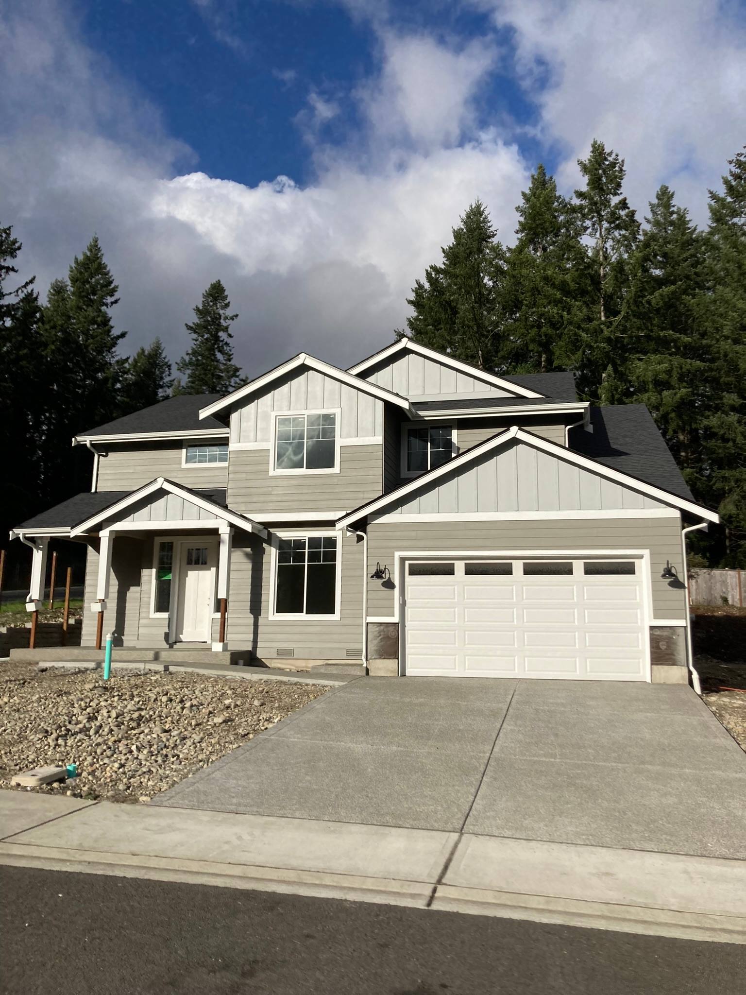 Two-story gray home with lap siding on the walls and board and batten on the gables